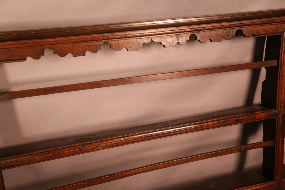 A Georgian dark oak plate rack featuring a scalloped top frieze, horizontal retaining bars, and side alcoves with shaped arch cutouts. View VIII