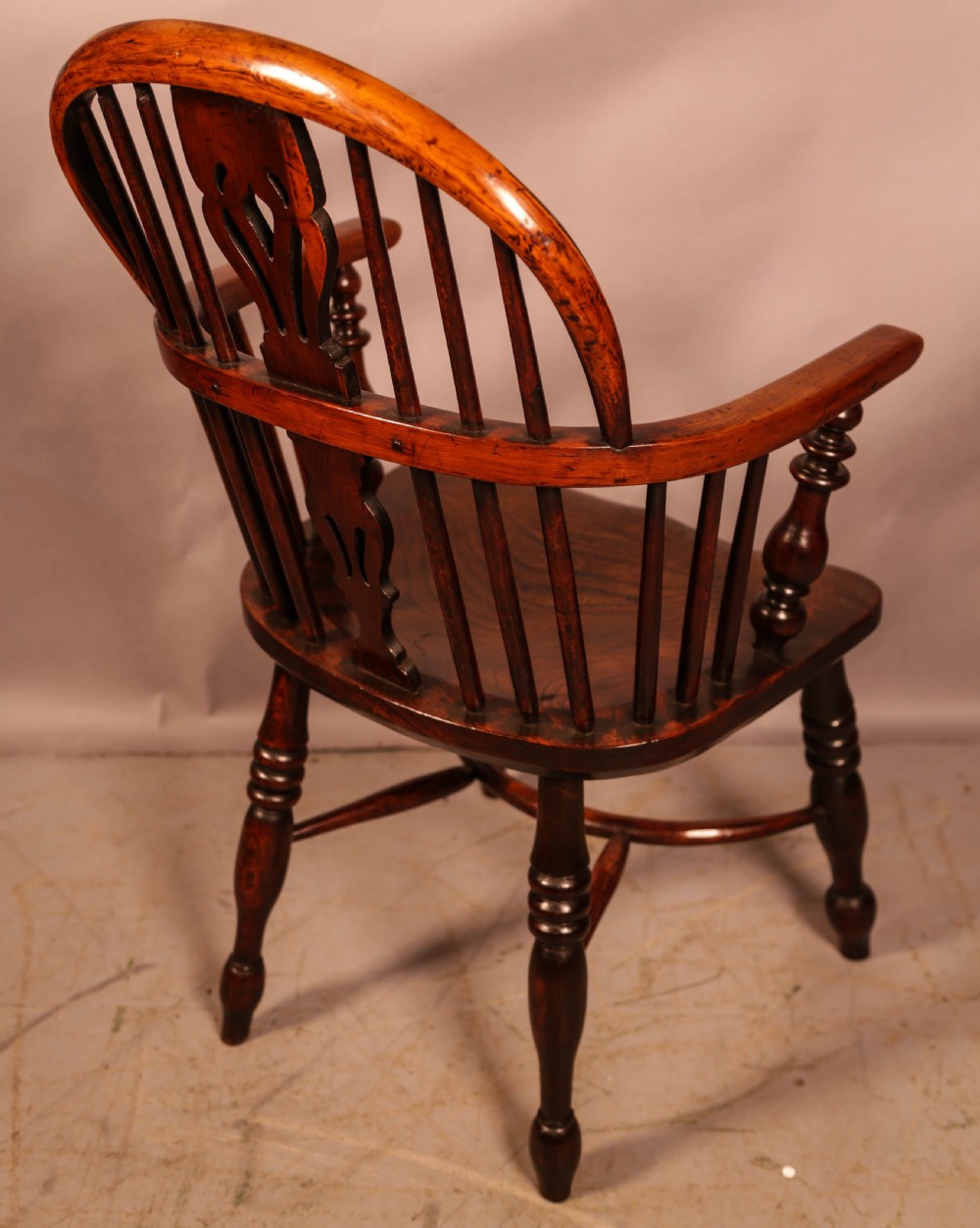 A yew wood Windsor armchair featuring a low back with turned spindles, a pierced fretwork central splat, curved armrests, a shaped solid seat, and turned legs joined by a crinoline stretcher. View II