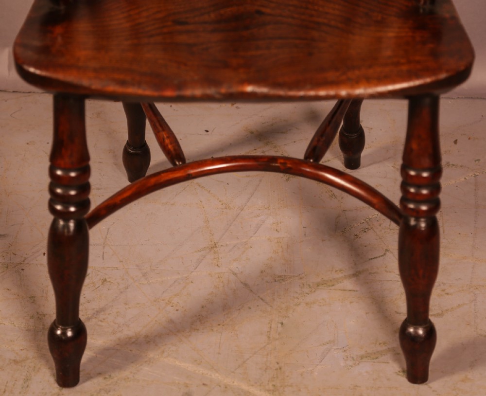A yew wood Windsor armchair featuring a low back with turned spindles, a pierced fretwork central splat, curved armrests, a shaped solid seat, and turned legs joined by a crinoline stretcher. View III