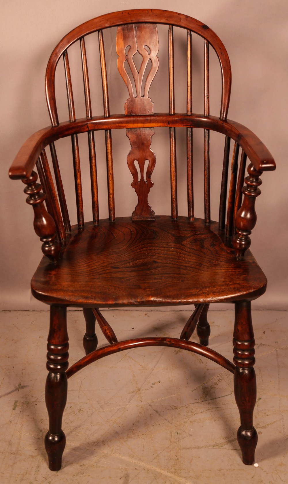 A yew wood Windsor armchair featuring a low back with turned spindles, a pierced fretwork central splat, curved armrests, a shaped solid seat, and turned legs joined by a crinoline stretcher. View IV
