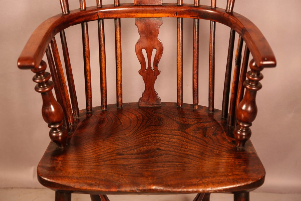 A yew wood Windsor armchair featuring a low back with turned spindles, a pierced fretwork central splat, curved armrests, a shaped solid seat, and turned legs joined by a crinoline stretcher. View V