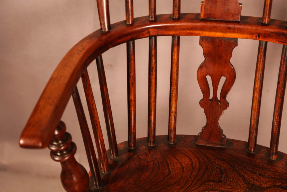 A yew wood Windsor armchair featuring a low back with turned spindles, a pierced fretwork central splat, curved armrests, a shaped solid seat, and turned legs joined by a crinoline stretcher. View VII