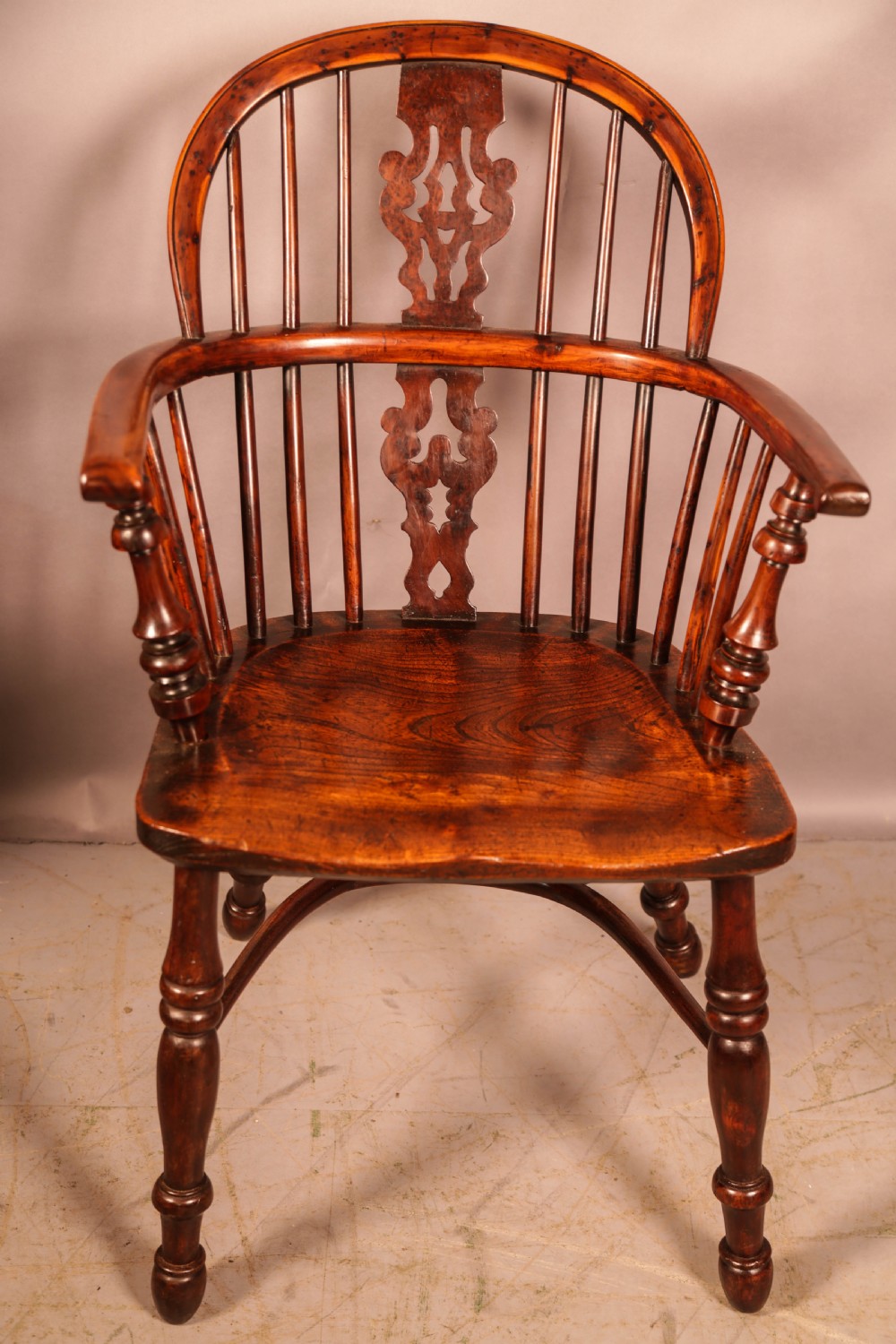 An antique yew wood Windsor armchair featuring a pierced splat, spindle back, shaped wooden seat, and turned legs. View III