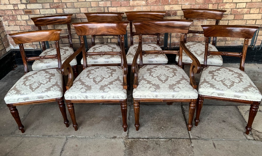 A set of eight Victorian mahogany dining chairs featuring curved top rails and patterned upholstered seats arranged in rows.