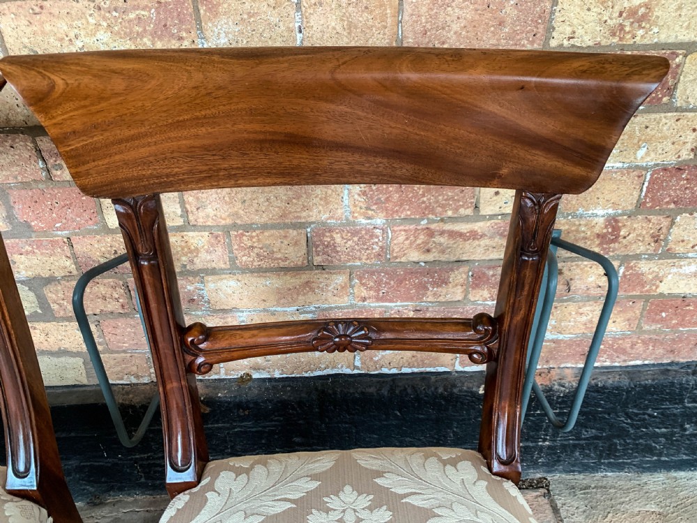 A set of eight Victorian mahogany dining chairs featuring curved top rails and patterned upholstered seats arranged in rows. View IX