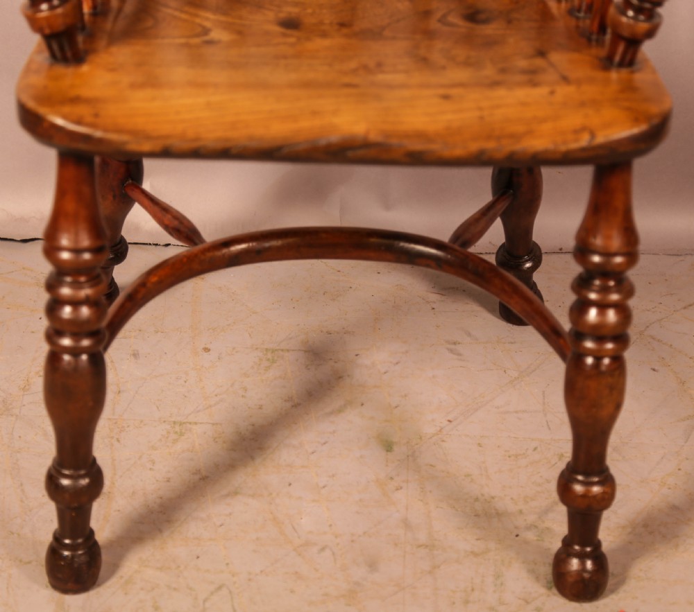 An antique yew wood Windsor armchair featuring a pierced back splat, spindle backrest, turned legs, and a crinoline stretcher. View V