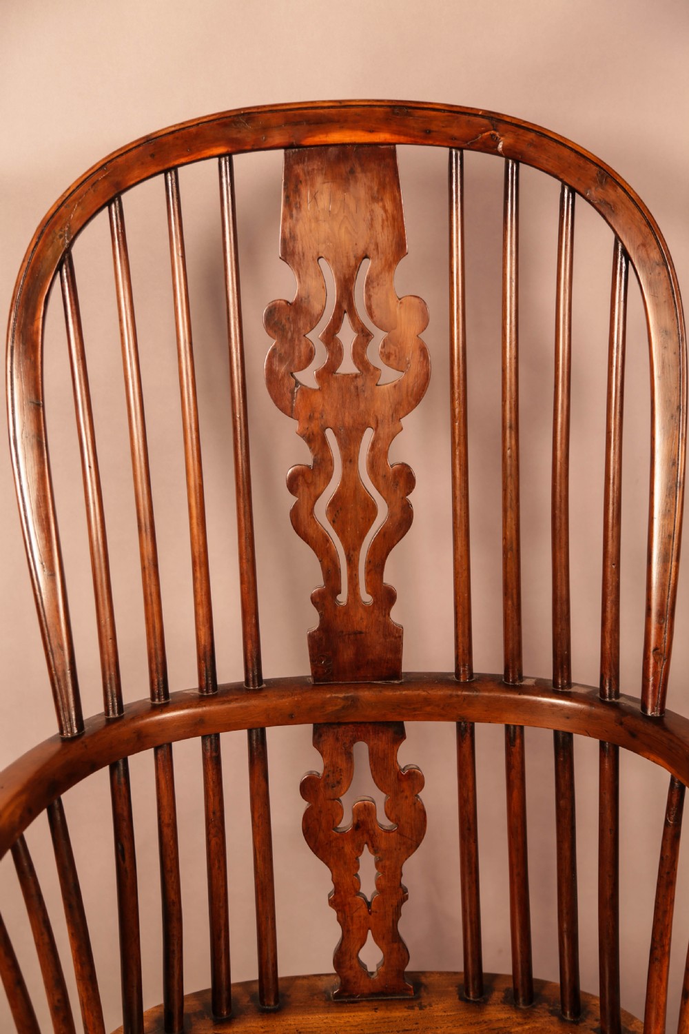 An antique yew wood Windsor armchair featuring a pierced back splat, spindle backrest, turned legs, and a crinoline stretcher. View X