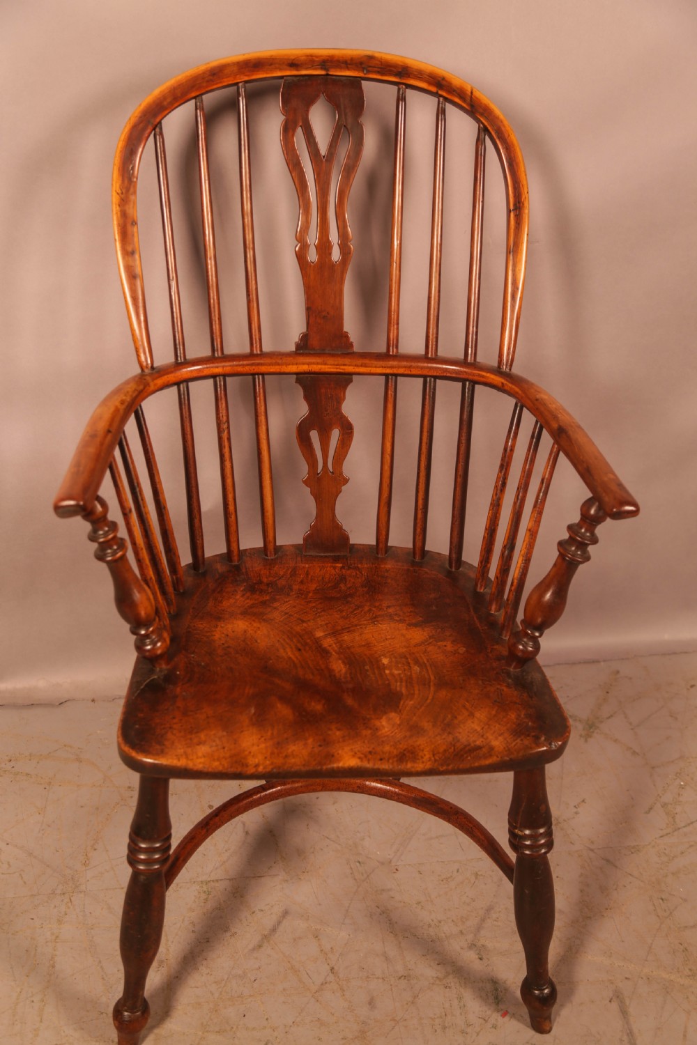 A 19th-century high back Windsor armchair made from yew wood with a shaped elm seat, turned legs, and a pierced decorative splat.