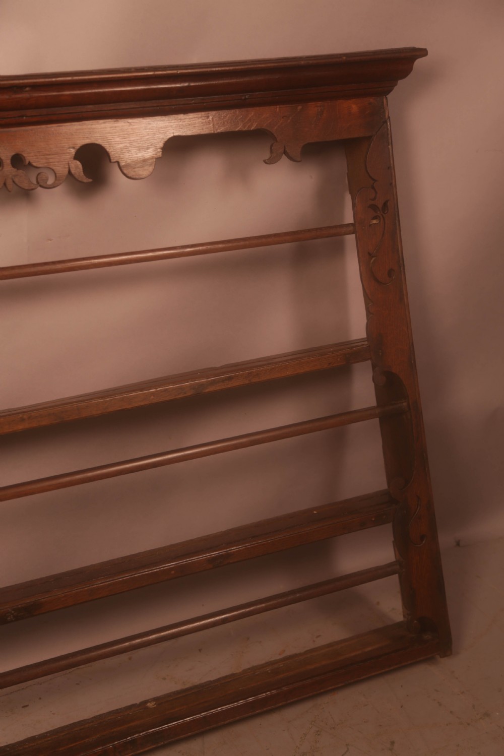 A Georgian dark oak wall-mounted plate rack featuring three horizontal shelves with retaining rails, a moulded top cornice, and decorative fretwork aprons. View V