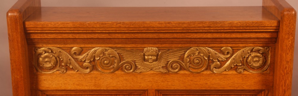 A late Victorian oak reading stand featuring recessed side panels and a decorative cast brass frieze with a central cherub motif. View IV