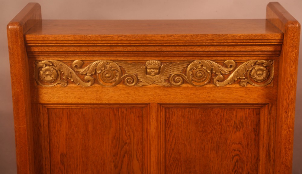 A late Victorian oak reading stand featuring recessed side panels and a decorative cast brass frieze with a central cherub motif. View VI