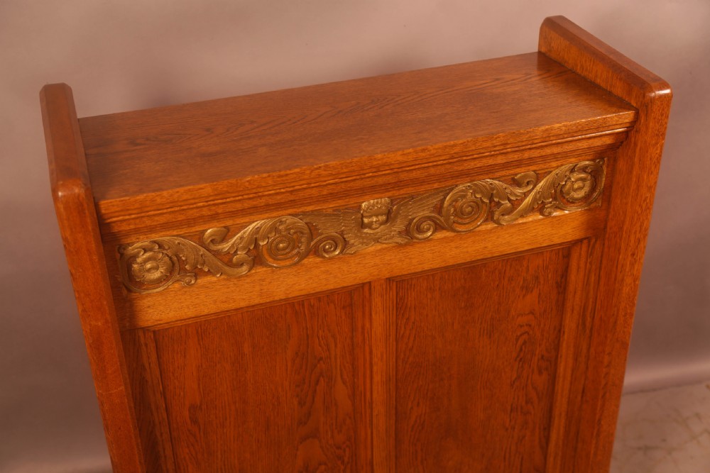 A late Victorian oak reading stand featuring recessed side panels and a decorative cast brass frieze with a central cherub motif. View VIII