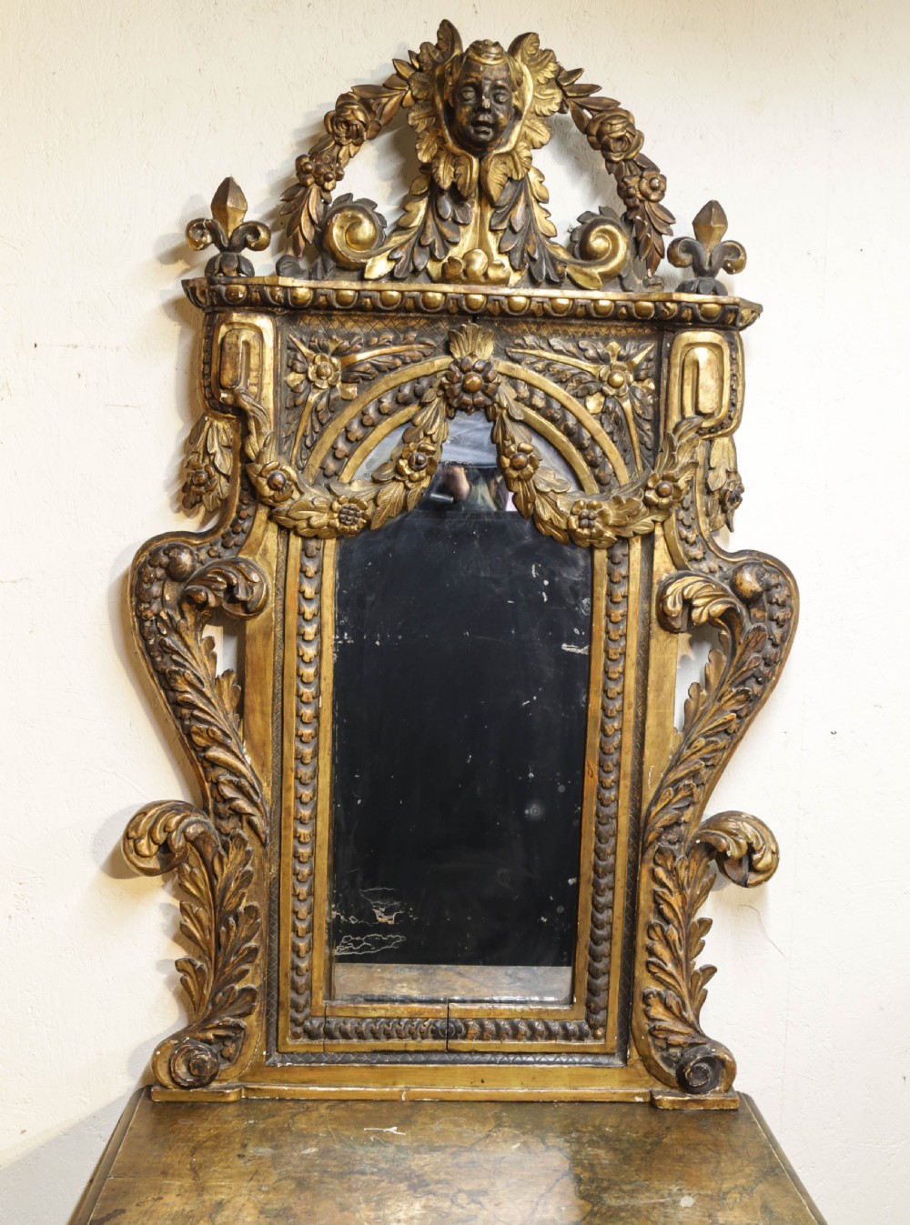 An 18th century Italian console table and matching mirror featuring heavily carved giltwood, putti supports, and ornate floral motifs. View VII