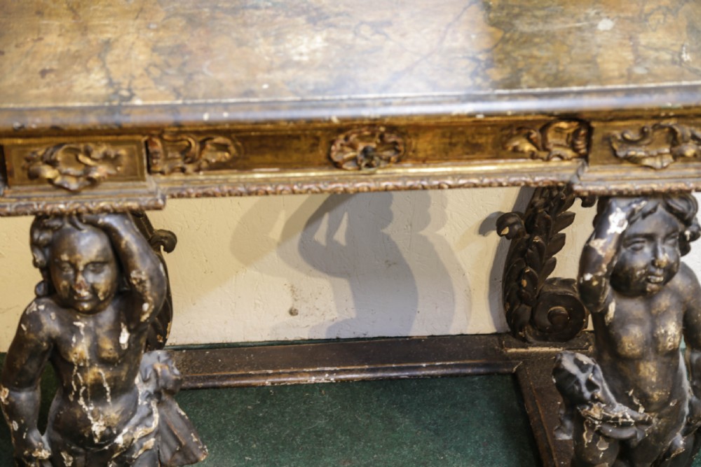 An 18th century Italian console table and matching mirror featuring heavily carved giltwood, putti supports, and ornate floral motifs. View XIII