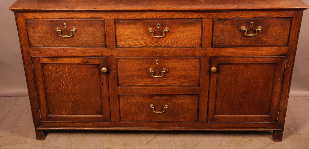 A Georgian oak serving dresser featuring multiple drawers, panelled cupboards, and a raised top tier with small drawers and arched cut-outs. View II