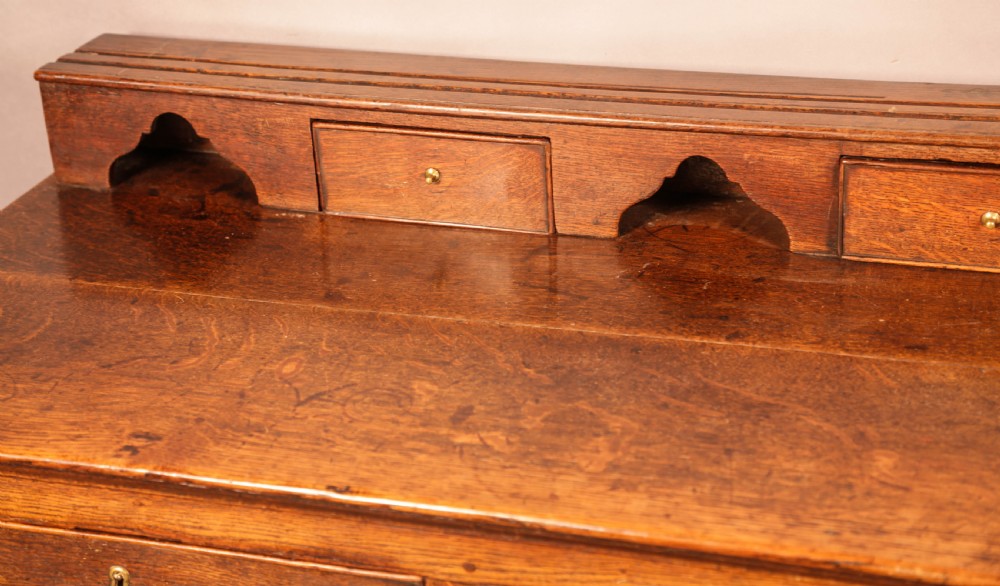 A Georgian oak serving dresser featuring multiple drawers, panelled cupboards, and a raised top tier with small drawers and arched cut-outs. View X