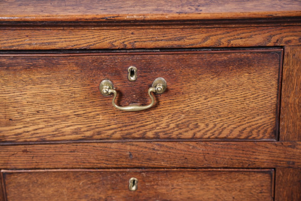 A Georgian oak serving dresser featuring multiple drawers, panelled cupboards, and a raised top tier with small drawers and arched cut-outs. View XIV