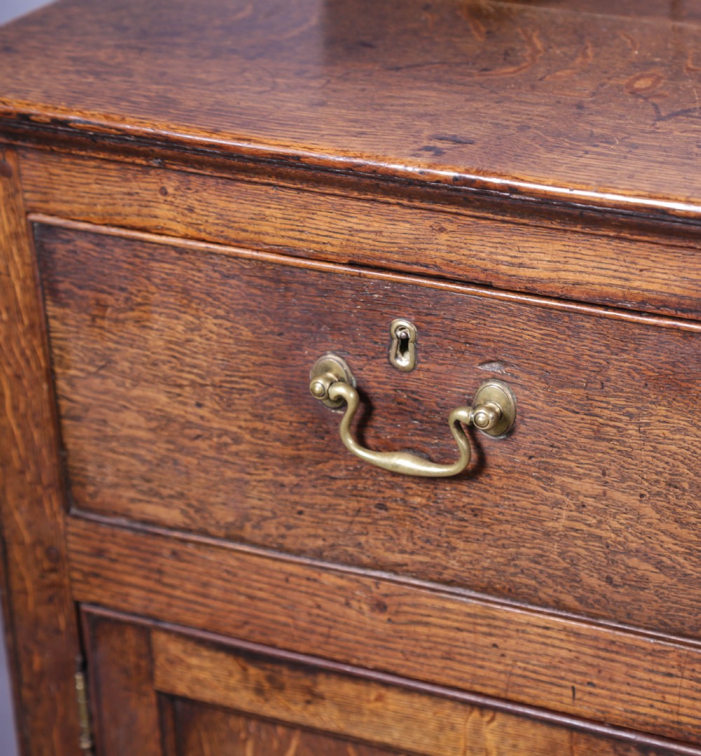 A Georgian oak serving dresser featuring multiple drawers, panelled cupboards, and a raised top tier with small drawers and arched cut-outs. View XV