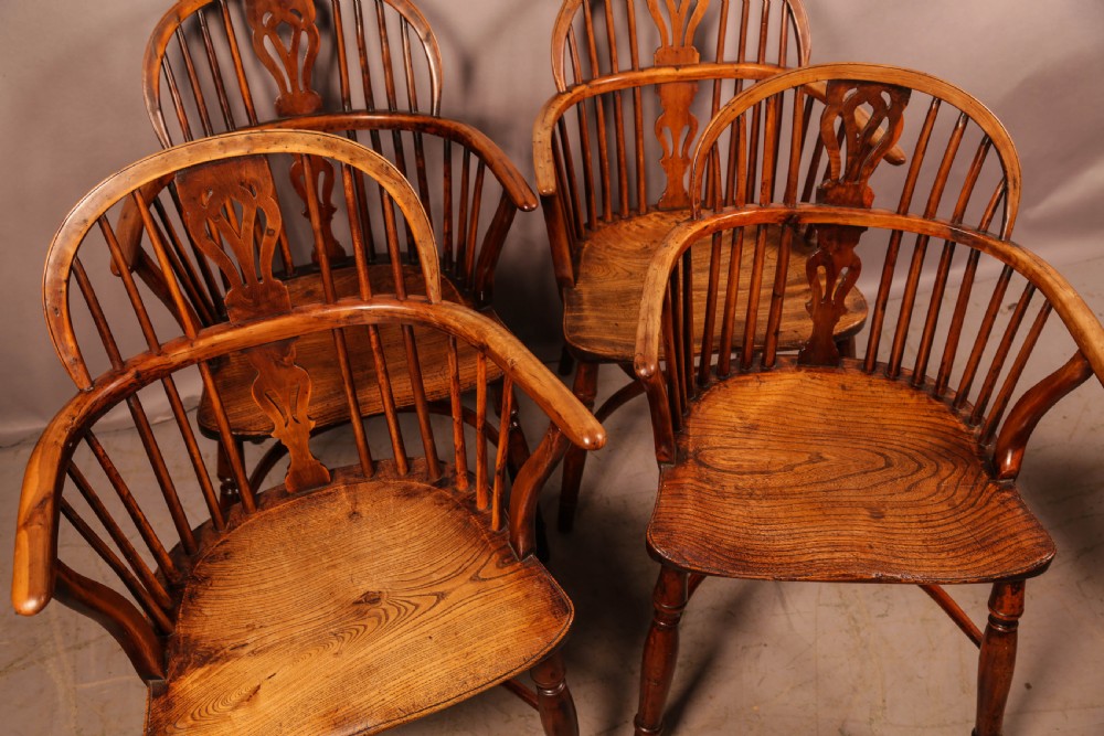 A set of four wooden Windsor armchairs featuring pierced splats, spindle backs, and sculpted seats. View IV