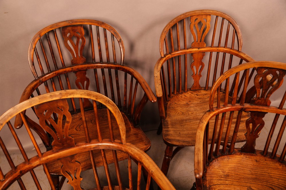 A set of four wooden Windsor armchairs featuring pierced splats, spindle backs, and sculpted seats. View V
