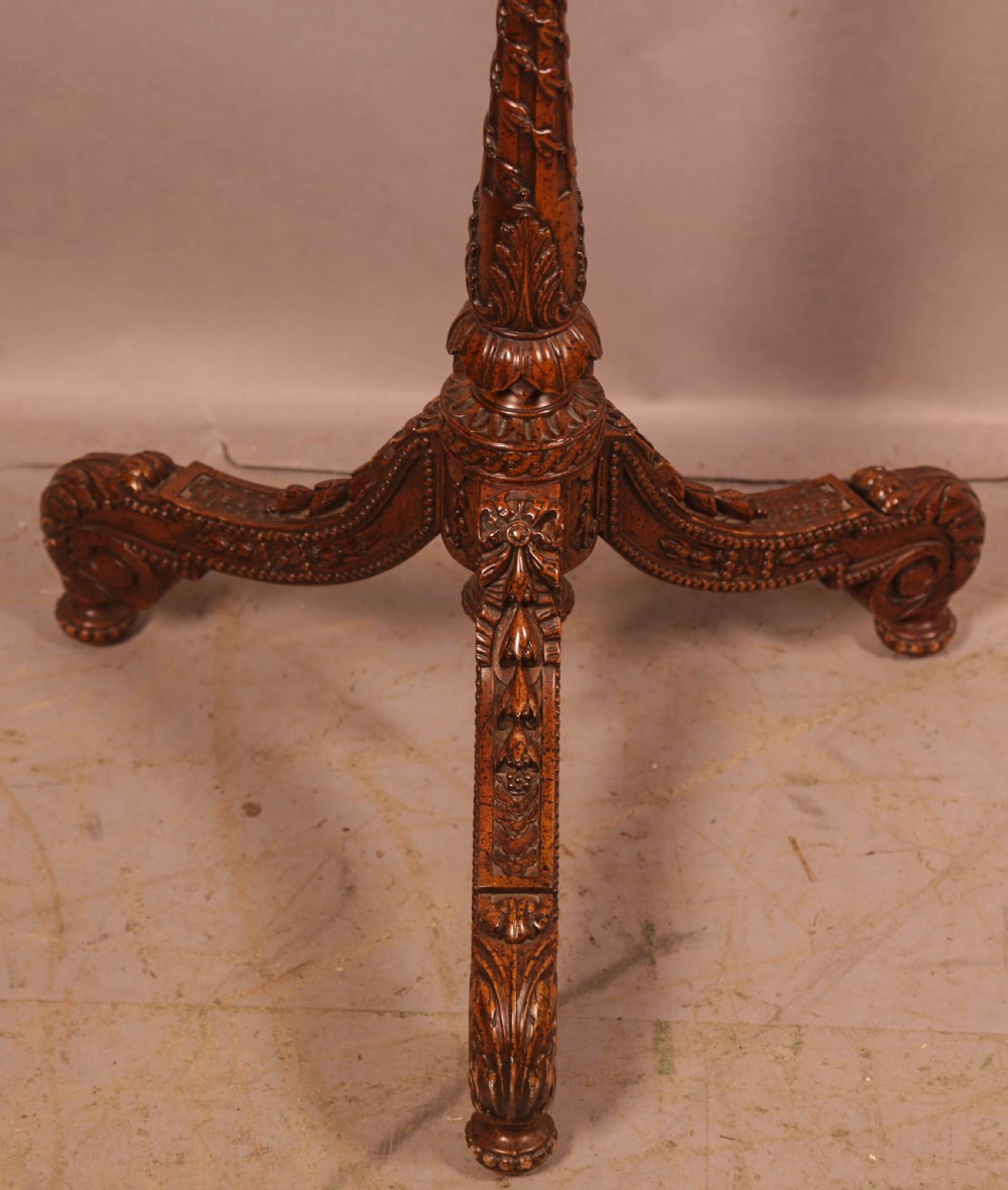 A nineteenth-century dark wood pole screen featuring an embroidered floral tapestry panel mounted on a brass rod with a heavily carved tripod base. View VI