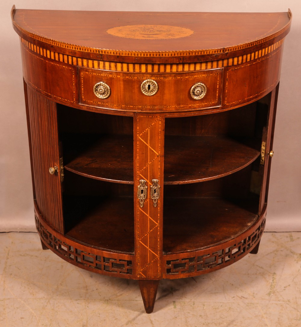 An eighteenth-century mahogany demi-lune cabinet featuring intricate geometric inlay, tambour doors, and brass hardware. View III