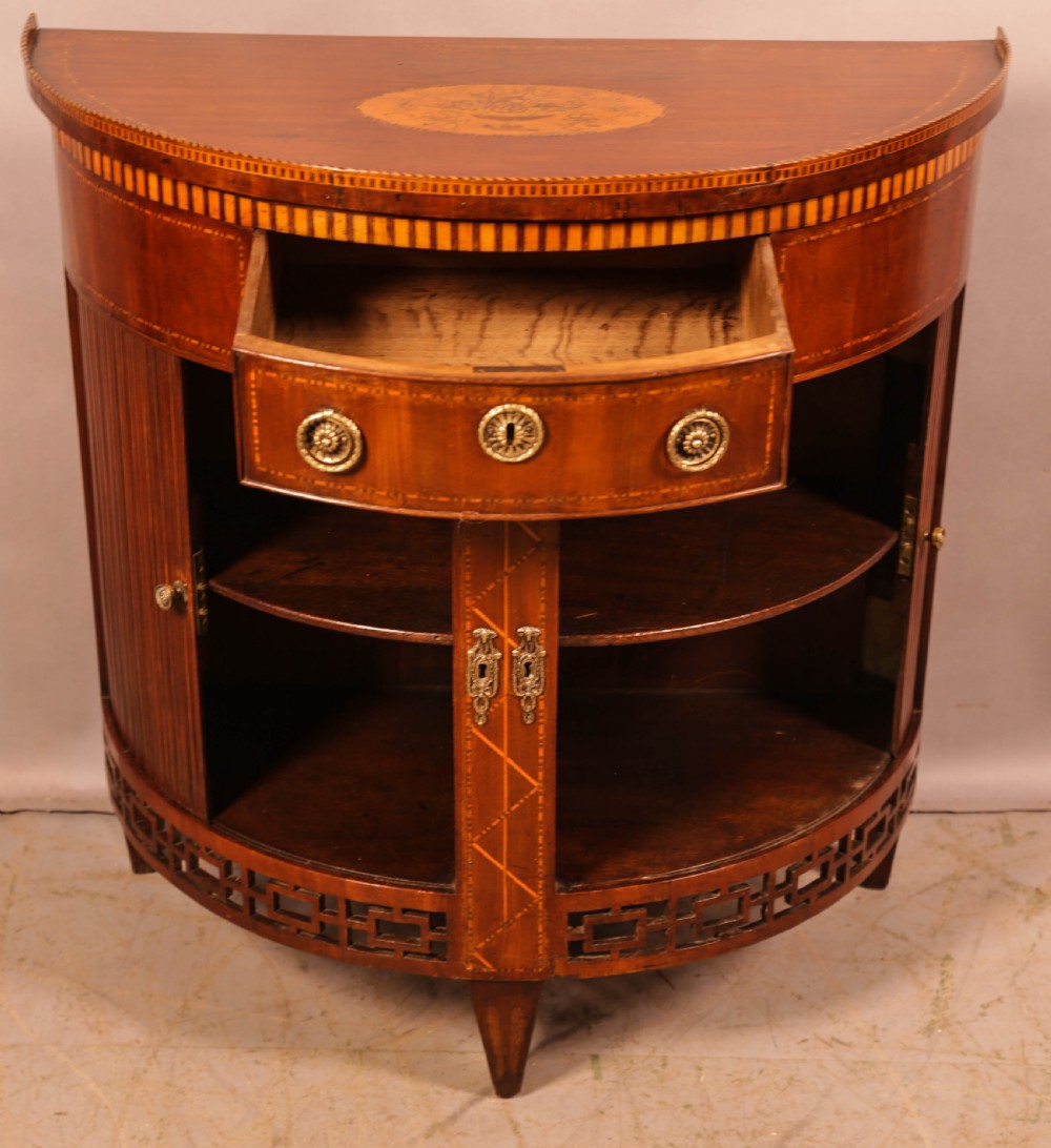 An eighteenth-century mahogany demi-lune cabinet featuring intricate geometric inlay, tambour doors, and brass hardware. View IV