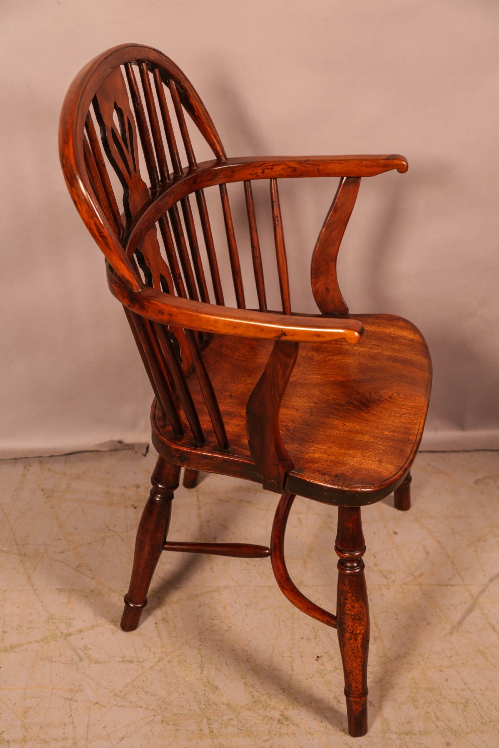 An English yew wood low-back Windsor armchair featuring a pierced splat, spindle back, shaped seat, turned legs, and a curved stretcher. View II