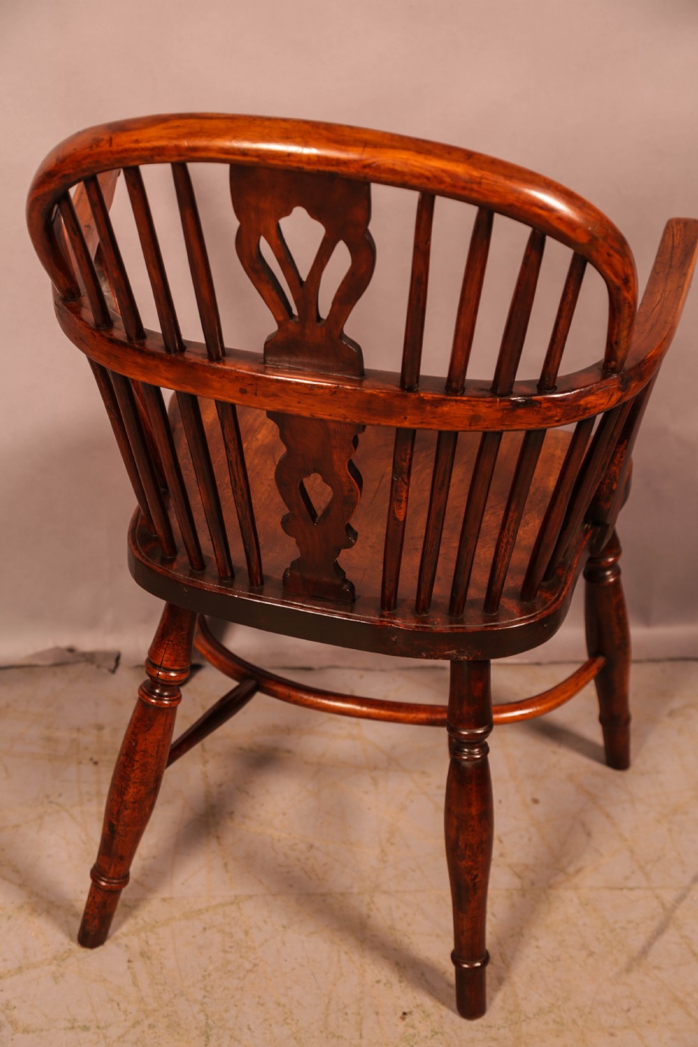 An English yew wood low-back Windsor armchair featuring a pierced splat, spindle back, shaped seat, turned legs, and a curved stretcher. View III
