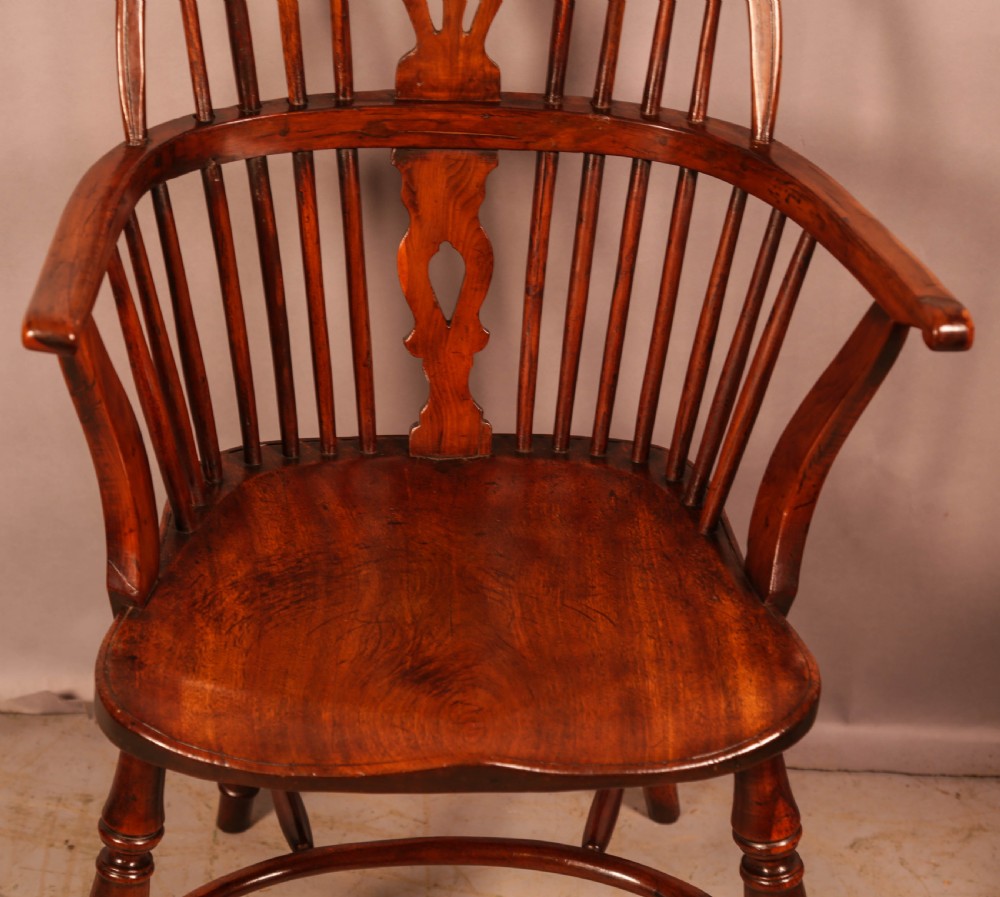 An English yew wood low-back Windsor armchair featuring a pierced splat, spindle back, shaped seat, turned legs, and a curved stretcher. View IV