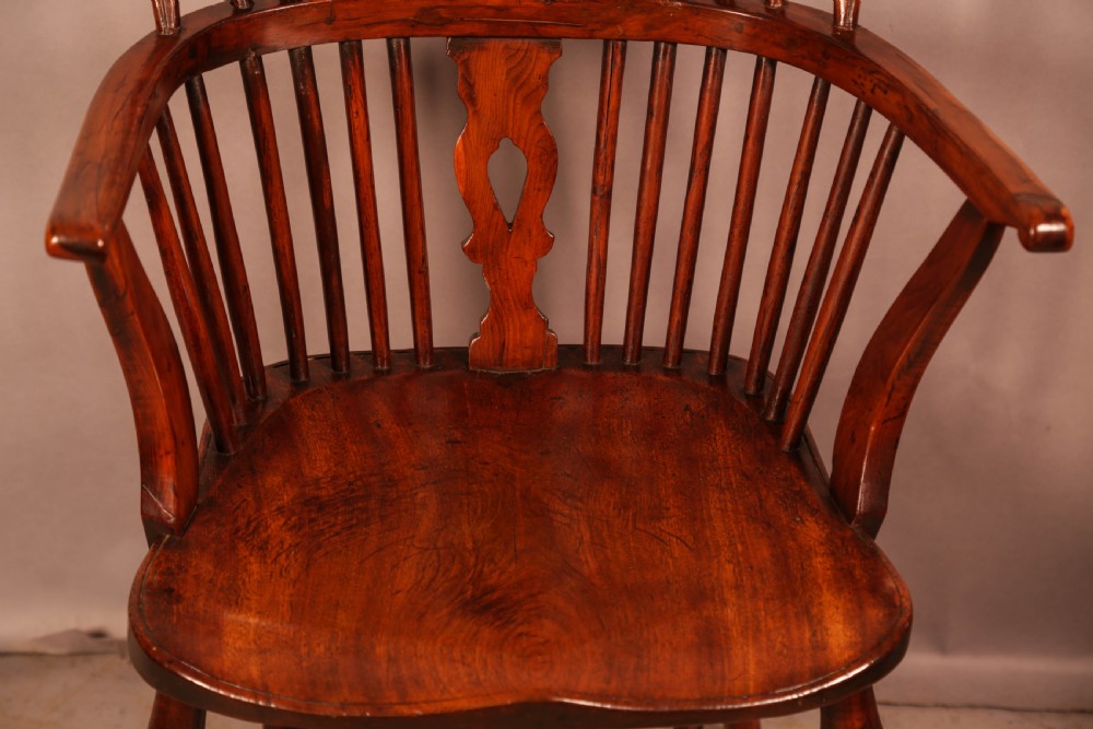 An English yew wood low-back Windsor armchair featuring a pierced splat, spindle back, shaped seat, turned legs, and a curved stretcher. View V