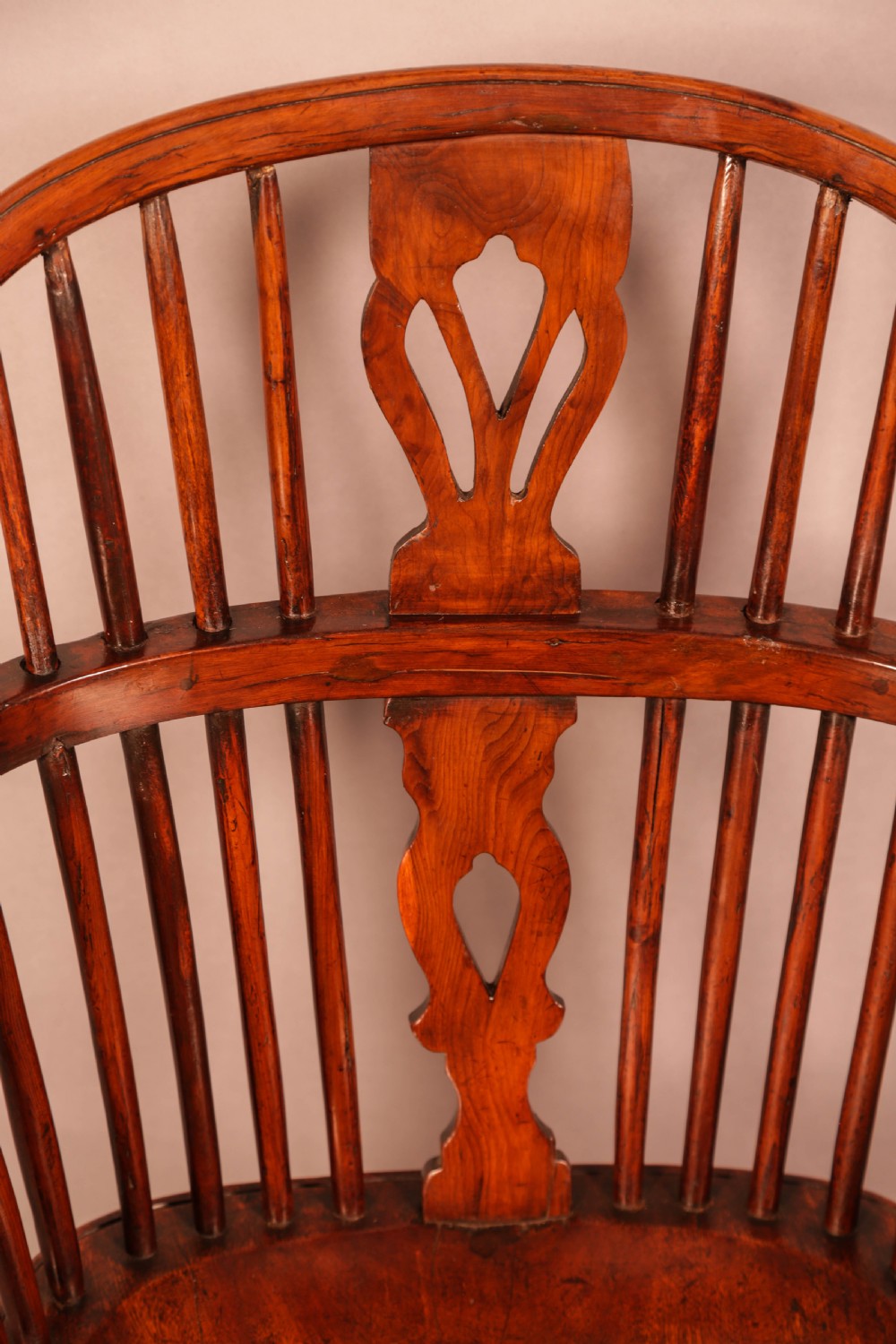 An English yew wood low-back Windsor armchair featuring a pierced splat, spindle back, shaped seat, turned legs, and a curved stretcher. View XI