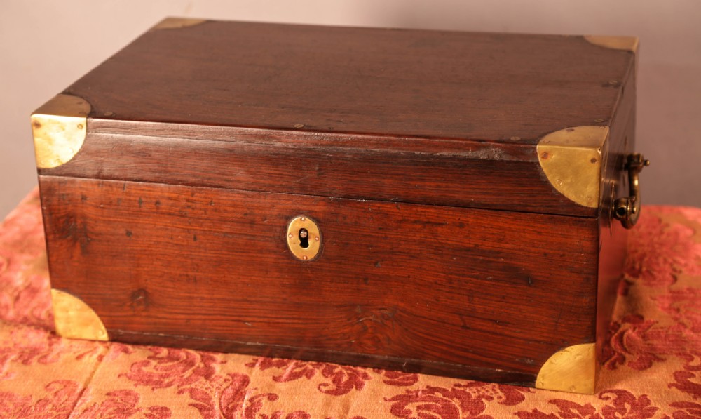 A rectangular rosewood campaign box featuring brass corner brackets, a central keyhole escutcheon, and side carry handles.