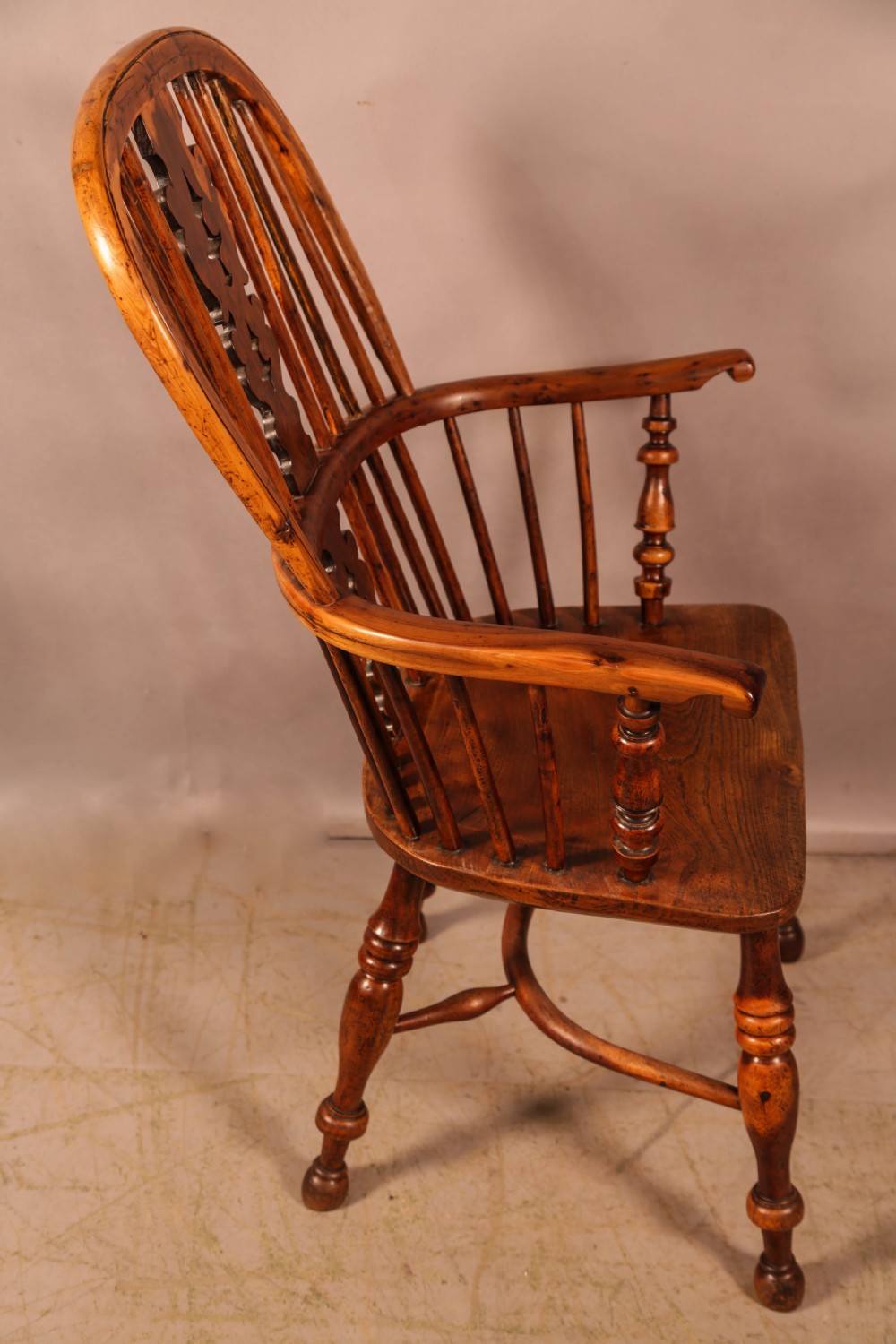 An antique yew wood high-back Windsor armchair featuring a pierced decorative splat, slender spindles, contoured seat, and turned legs with a curved stretcher. View II
