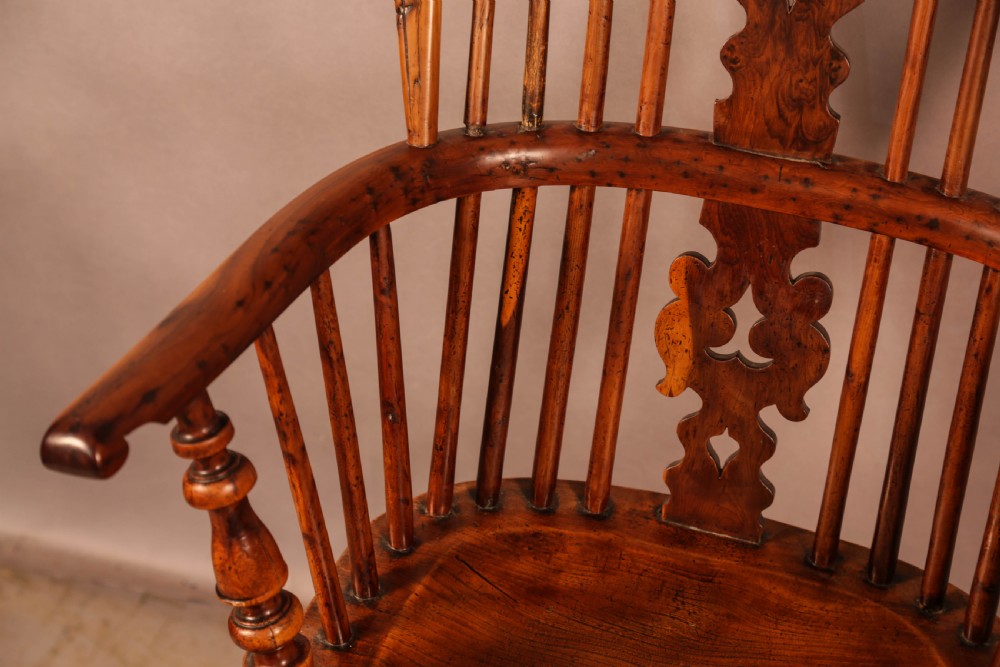 An antique yew wood high-back Windsor armchair featuring a pierced decorative splat, slender spindles, contoured seat, and turned legs with a curved stretcher. View III