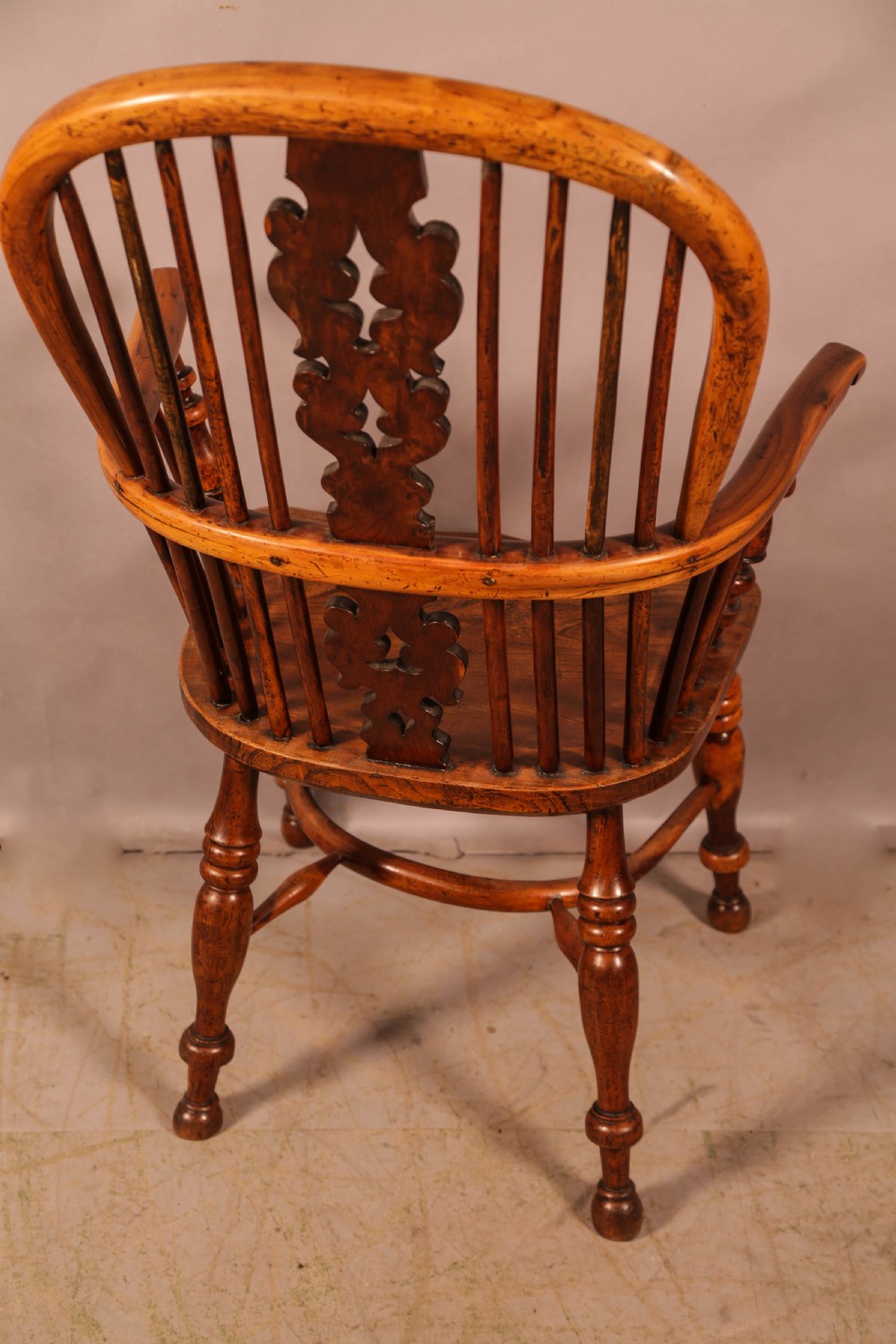 An antique yew wood high-back Windsor armchair featuring a pierced decorative splat, slender spindles, contoured seat, and turned legs with a curved stretcher. View IV