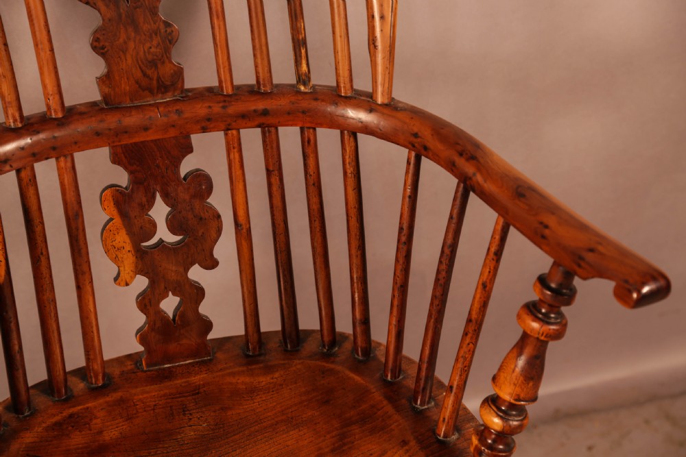 An antique yew wood high-back Windsor armchair featuring a pierced decorative splat, slender spindles, contoured seat, and turned legs with a curved stretcher. View V