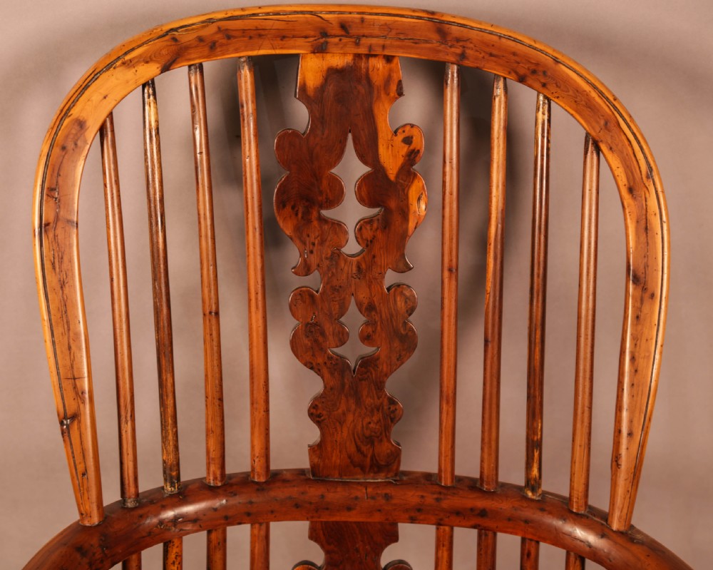 An antique yew wood high-back Windsor armchair featuring a pierced decorative splat, slender spindles, contoured seat, and turned legs with a curved stretcher. View VI