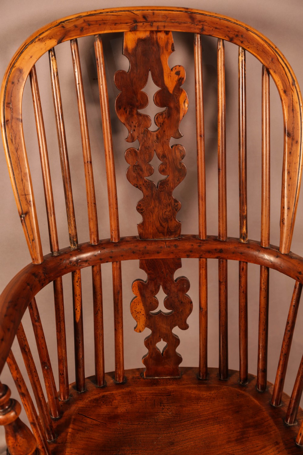 An antique yew wood high-back Windsor armchair featuring a pierced decorative splat, slender spindles, contoured seat, and turned legs with a curved stretcher. View VII