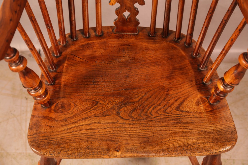 An antique yew wood high-back Windsor armchair featuring a pierced decorative splat, slender spindles, contoured seat, and turned legs with a curved stretcher. View VIII
