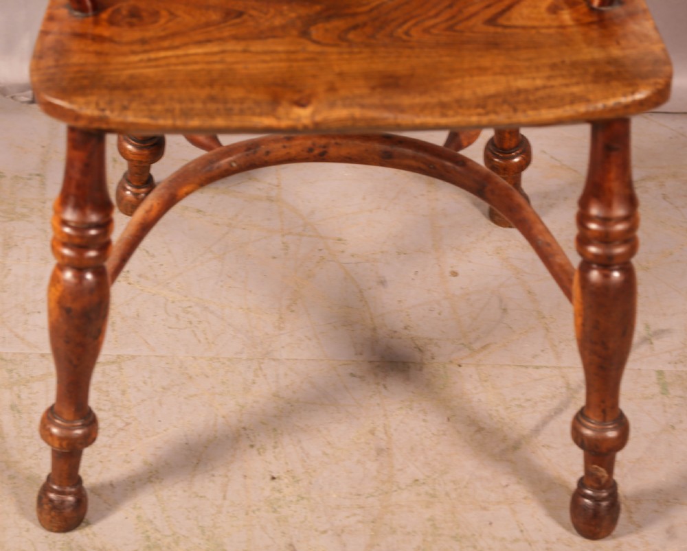 An antique yew wood high-back Windsor armchair featuring a pierced decorative splat, slender spindles, contoured seat, and turned legs with a curved stretcher. View X
