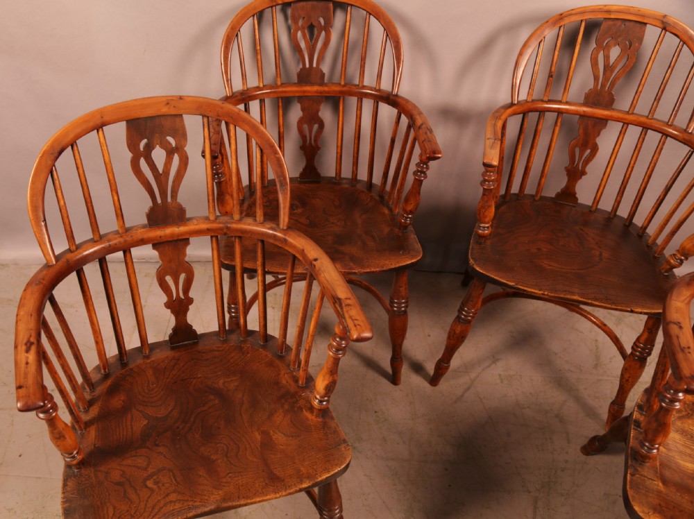 A matching set of four wooden Windsor armchairs featuring pierced splat backs, turned spindles, and sculpted seats. View IV
