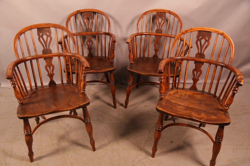 A matching set of four wooden Windsor armchairs featuring pierced splat backs, turned spindles, and sculpted seats. View VI
