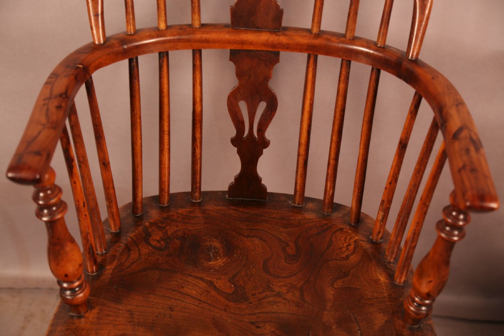 A matching set of four wooden Windsor armchairs featuring pierced splat backs, turned spindles, and sculpted seats. View X