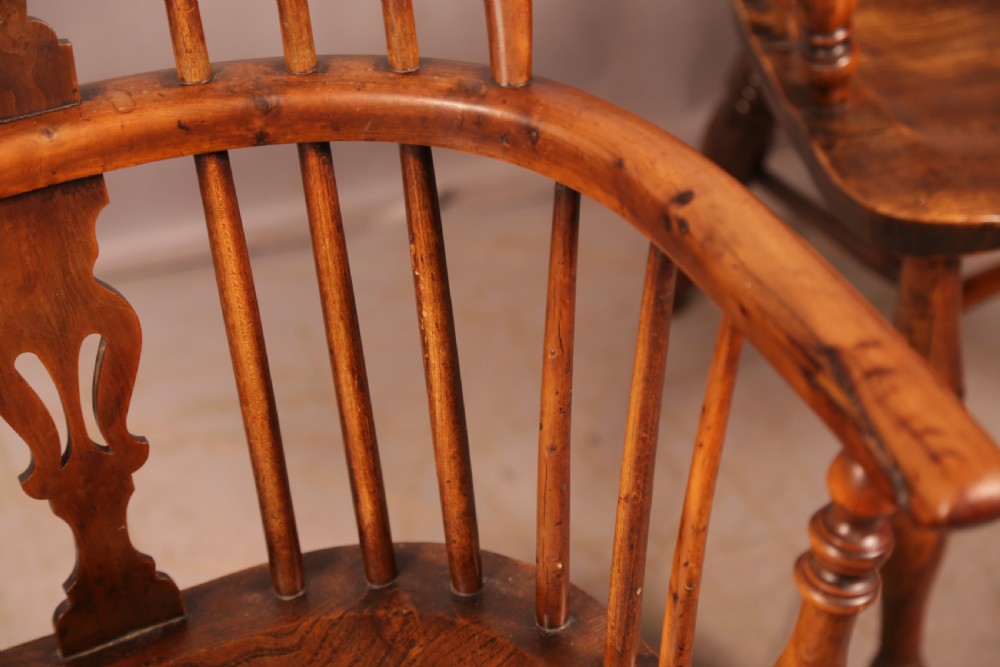 A matching set of four wooden Windsor armchairs featuring pierced splat backs, turned spindles, and sculpted seats. View XXI