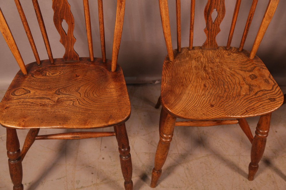 A matching set of four wooden Windsor chairs featuring shaped elm seats, stick-back spindles, and central pierced splats. View IV