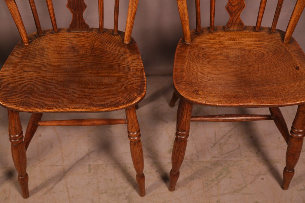 A matching set of four wooden Windsor chairs featuring shaped elm seats, stick-back spindles, and central pierced splats. View VII