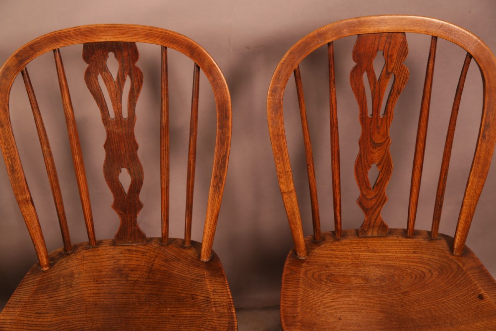 A matching set of four wooden Windsor chairs featuring shaped elm seats, stick-back spindles, and central pierced splats. View VIII