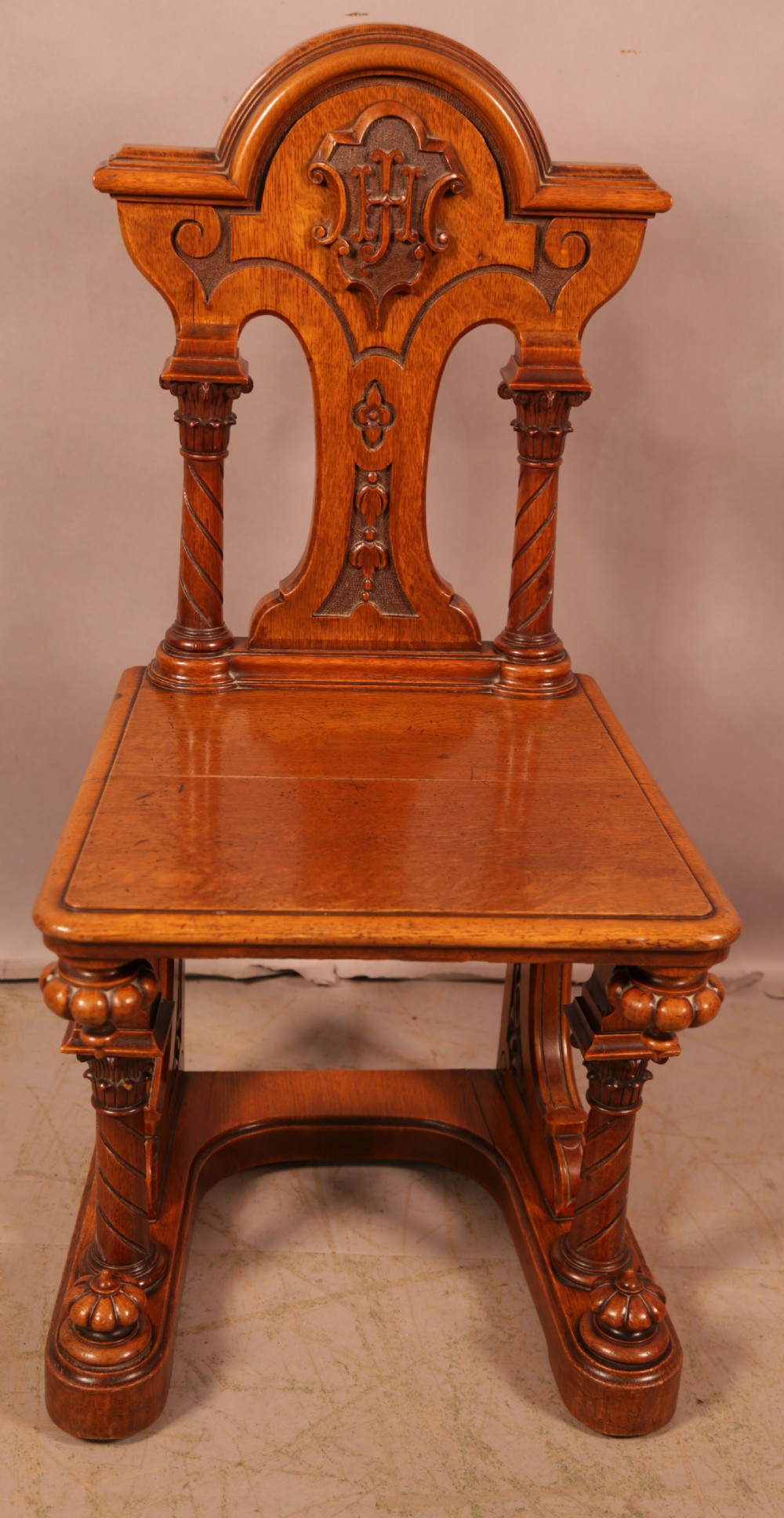 A matching pair of carved oak Victorian hall chairs featuring architectural columns and scrollwork crests. View II