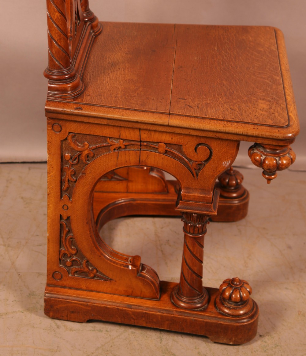A matching pair of carved oak Victorian hall chairs featuring architectural columns and scrollwork crests. View IV